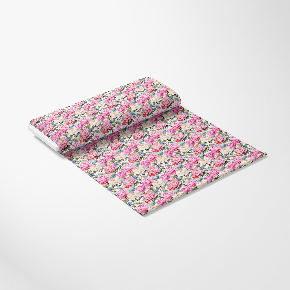 A roll of floral-patterned wrapping paper is partially unrolled on a white surface. The design features densely packed colorful flowers in shades of pink, red, yellow, and green on a light background.