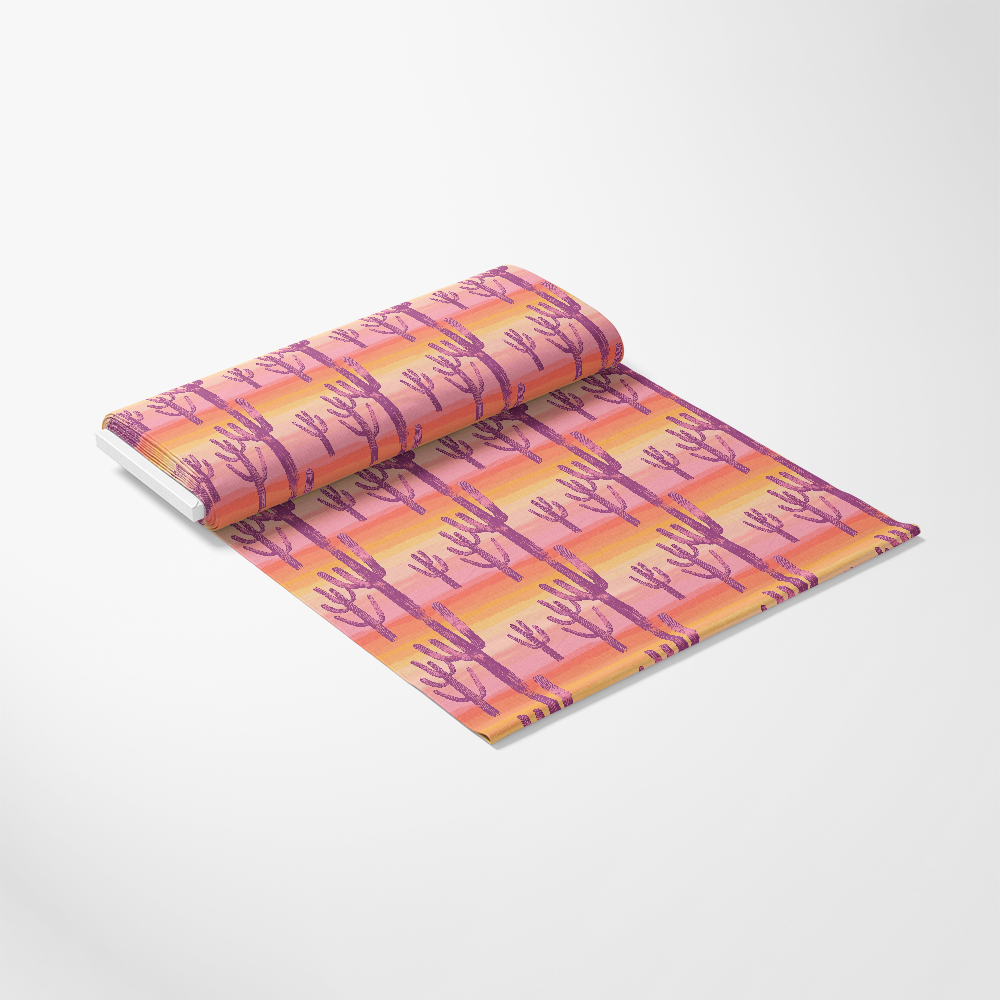 A roll of wallpaper with a pink cactus pattern on a gradient orange and yellow background, unrolled slightly on a white surface.