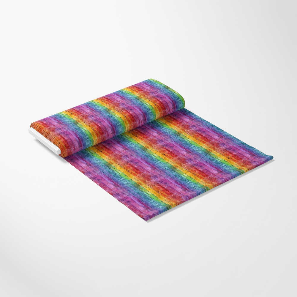 A roll of fabric partially unrolled on a white surface, featuring a repeating rainbow stripe pattern with textured, watercolor-like colors.