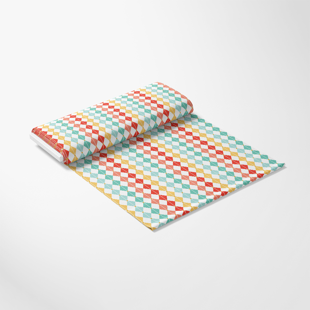 A roll of fabric with a colorful diamond pattern in red, blue, yellow, and green on a white background, partially unrolled on a plain surface.