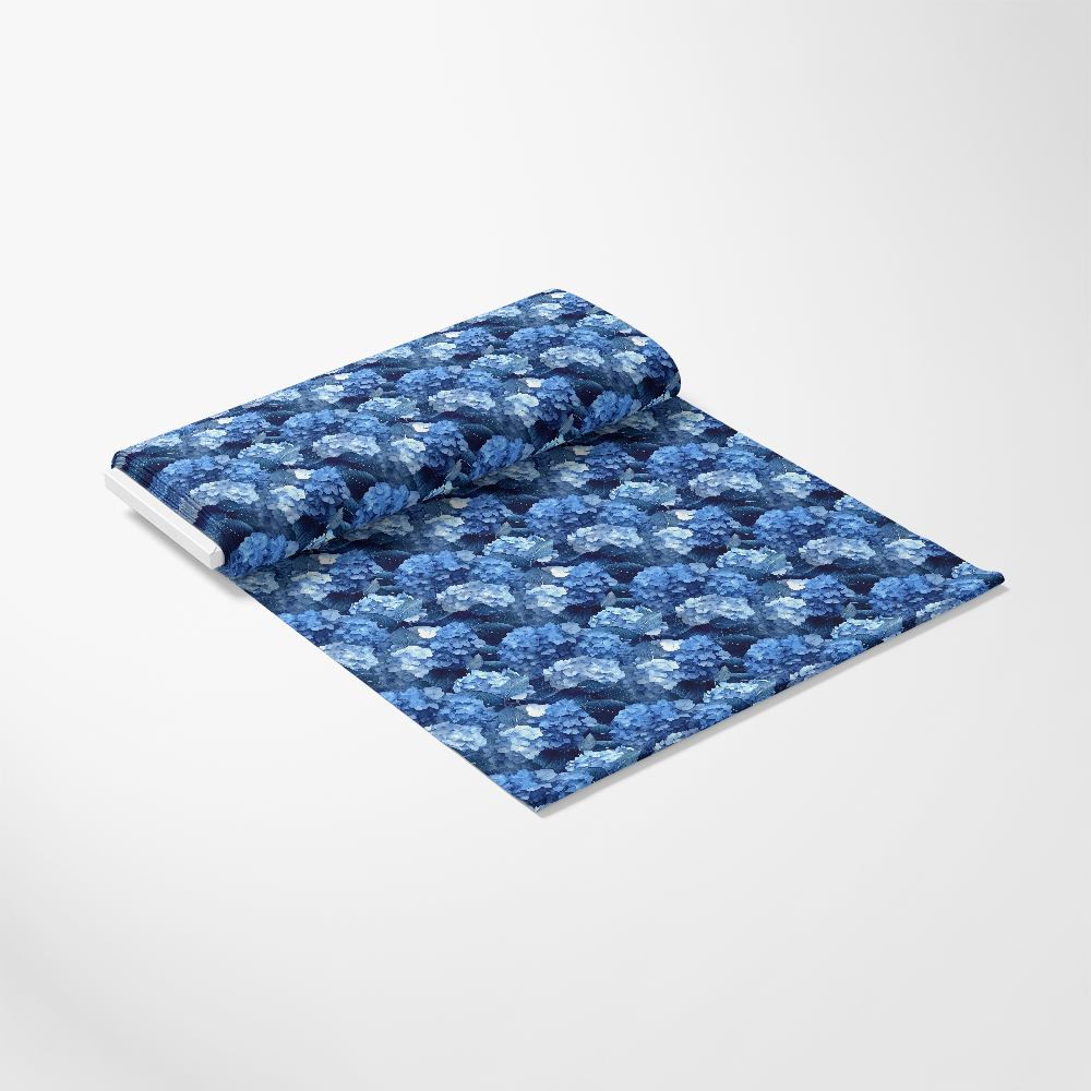 A roll of blue floral-patterned fabric partially unrolled on a white background.