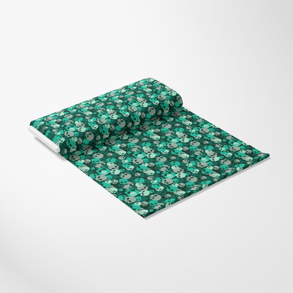 A roll of fabric with a green skull pattern displayed on a flat surface.