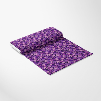 A roll of fabric featuring a purple camouflage pattern is partially unrolled on a plain white background.