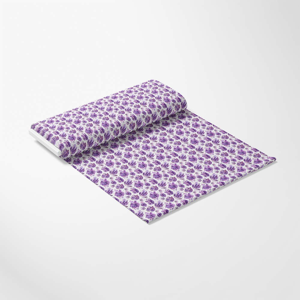 Roll of wallpaper with a purple floral pattern on a white background, unrolling towards the viewer on a plain surface.