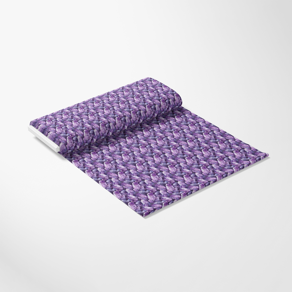 A roll of purple fabric with a floral pattern is partially unrolled on a plain white surface.