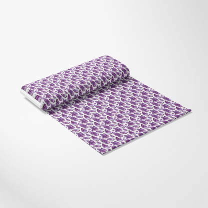 A roll of fabric with a repeating pattern of purple and white paisley design on a light background.