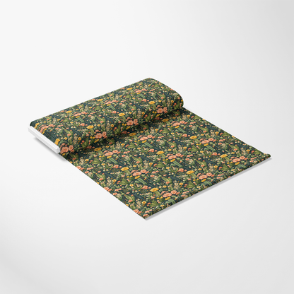 A roll of fabric partially unrolled, featuring a green background with a floral pattern in pink, orange, and yellow.