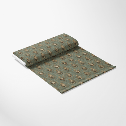 A rolled-out decorative wallpaper roll with a green background and intricate gold floral pattern, laying on a plain white surface.