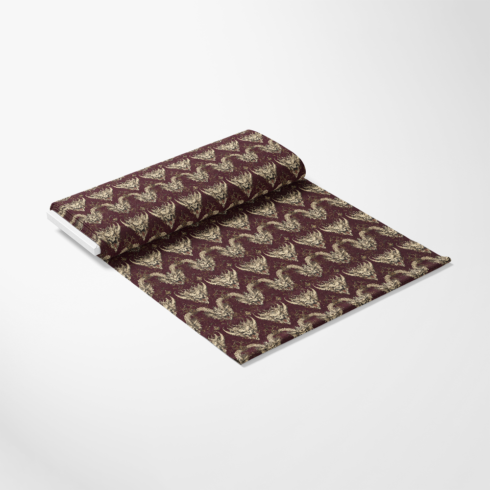 A roll of decorative fabric with a maroon background and gold floral pattern, partially unrolled on a white surface.