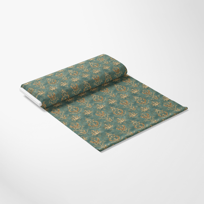 A roll of decorative wallpaper with a teal background and intricate gold floral patterns, partially unrolled on a white surface.
