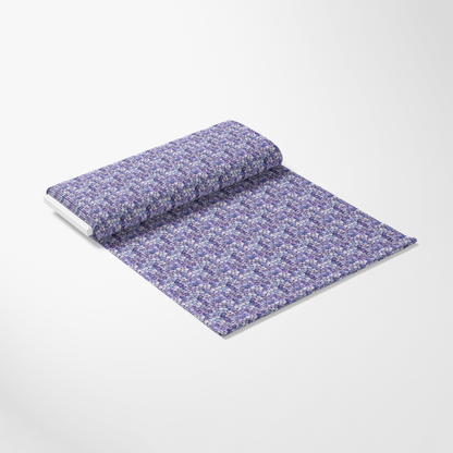 A roll of wallpaper featuring a purple and white floral pattern is partially unrolled on a plain surface.