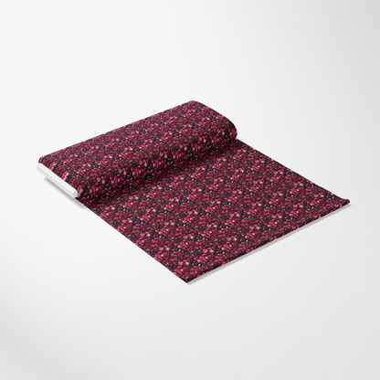 A roll of dark floral fabric with red and pink flowers on a white background.