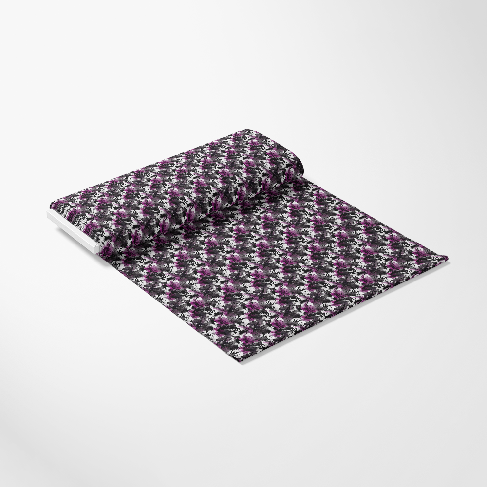 A roll of fabric partially unrolled, featuring a repeating floral pattern in shades of purple and white on a black background, displayed on a plain white surface.