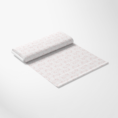 A roll of white wrapping paper with a subtle red floral pattern, partially unrolled on a plain white surface.