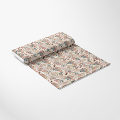 A roll of patterned fabric is partially unrolled on a white surface. The fabric features a repeating geometric and floral design in red, blue, and beige tones.