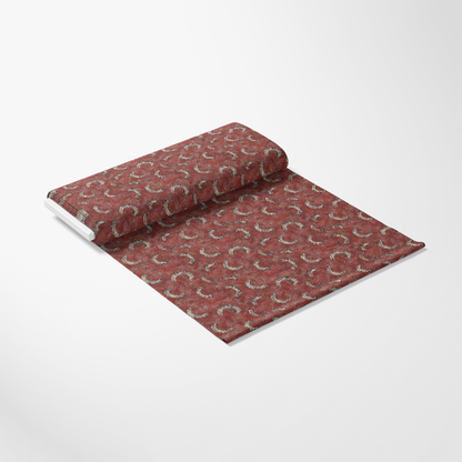 A roll of maroon wallpaper with a subtle, repeating horseshoe pattern is partially unrolled on a white background.