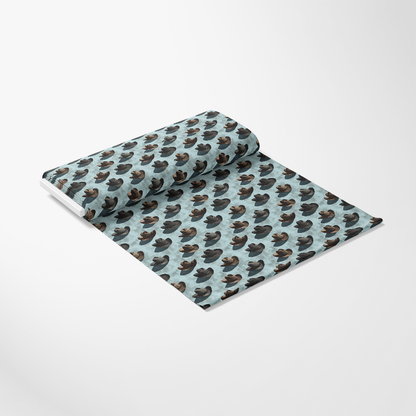 A roll of light blue fabric with a repeated pattern of brown and dark blue ducks.