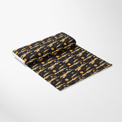 A rolled-out section of fabric featuring a black background with an abstract pattern of orange planets and rocket ships.