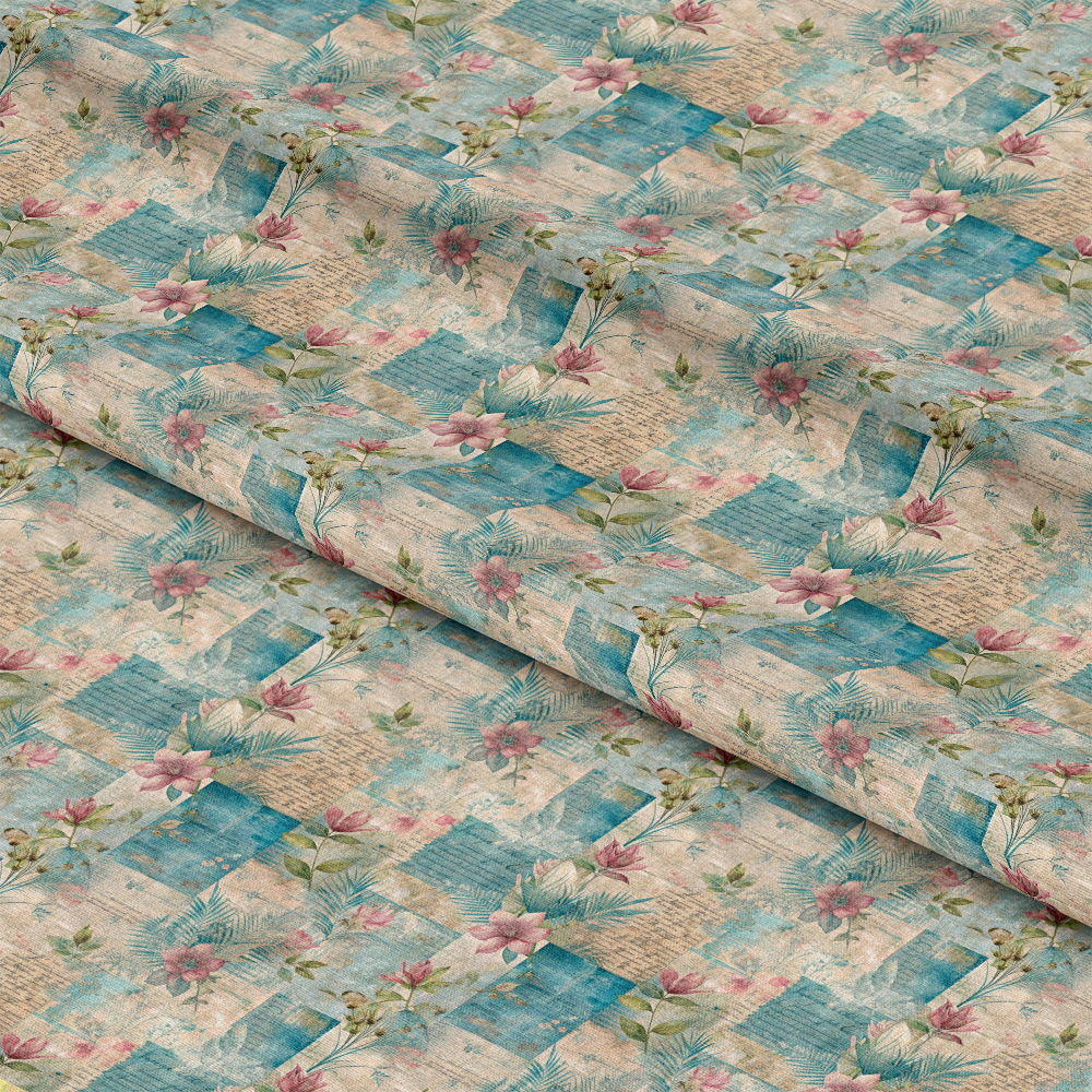 A fabric with a geometric patchwork pattern in shades of teal and beige, overlaid with pink flowers, green leaves, and subtle textured designs. The fabric is folded in layered sections.