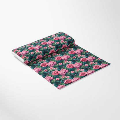 A roll of wrapping paper with a floral pattern featuring pink roses and green leaves on a white background.