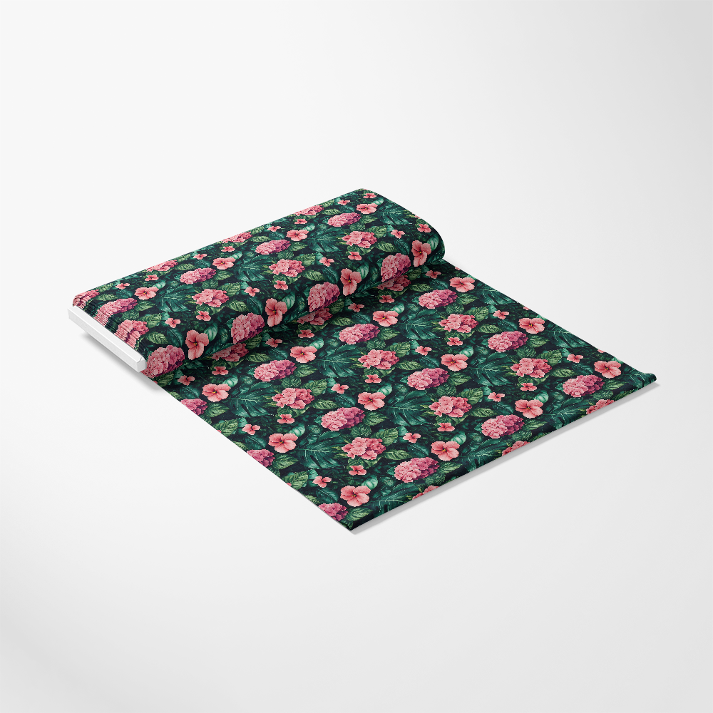A roll of fabric with a floral pattern featuring pink flowers and green leaves on a dark background, unrolled on a light gray surface.