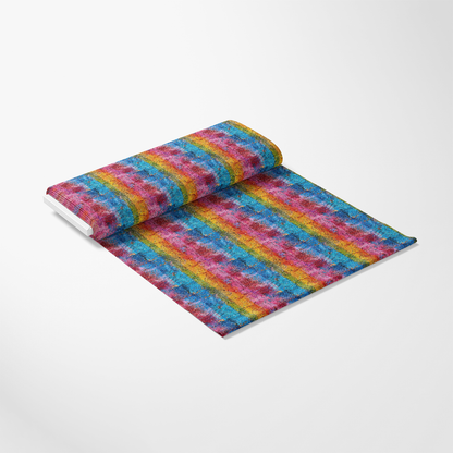A rolled-out sheet of fabric with a vibrant, multicolored striped pattern featuring red, blue, yellow, green, and purple tones, displayed on a plain white background.