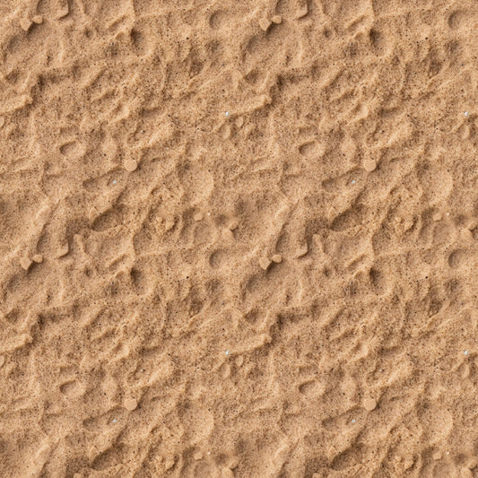 A close-up view of textured sand with small ripples and scattered pebbles.