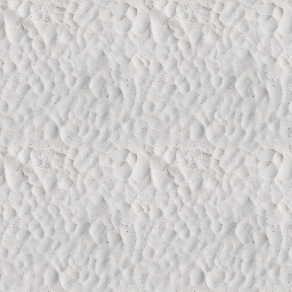 Close-up view of white sand with a pattern of small, uneven ridges and shallow depressions.