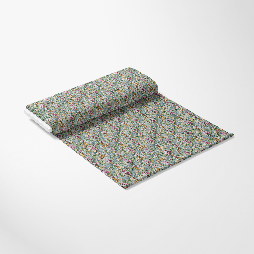 A roll of patterned fabric partially unrolled on a white surface. The fabric has a dense, multicolored floral design with green, pink, and blue hues.