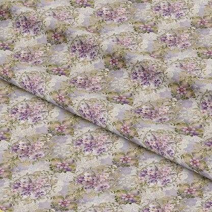 A close-up view of fabric with a repeating floral pattern featuring purple, pink, and white flowers with green leaves on a light background, displayed with gentle folds across the surface.